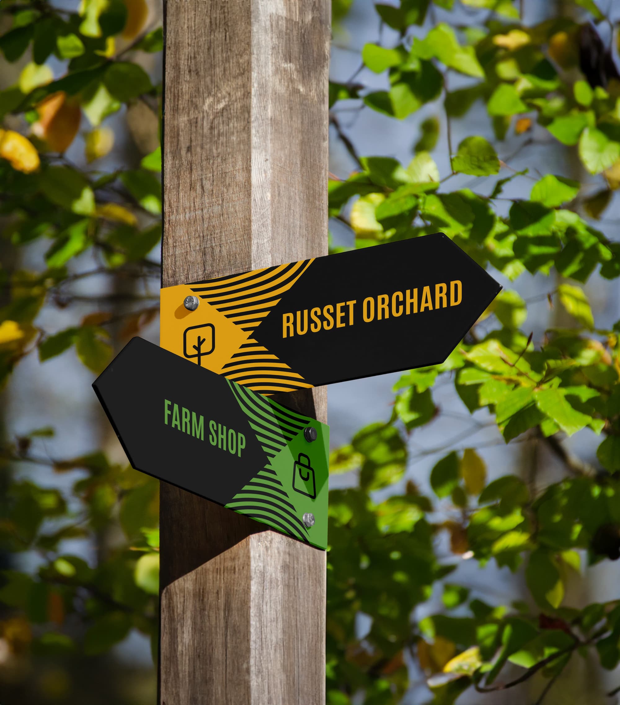 Chegworth Valley orchard signage with branded direction signs pointing to Russet Orchard and farm shop in English apple orchard.