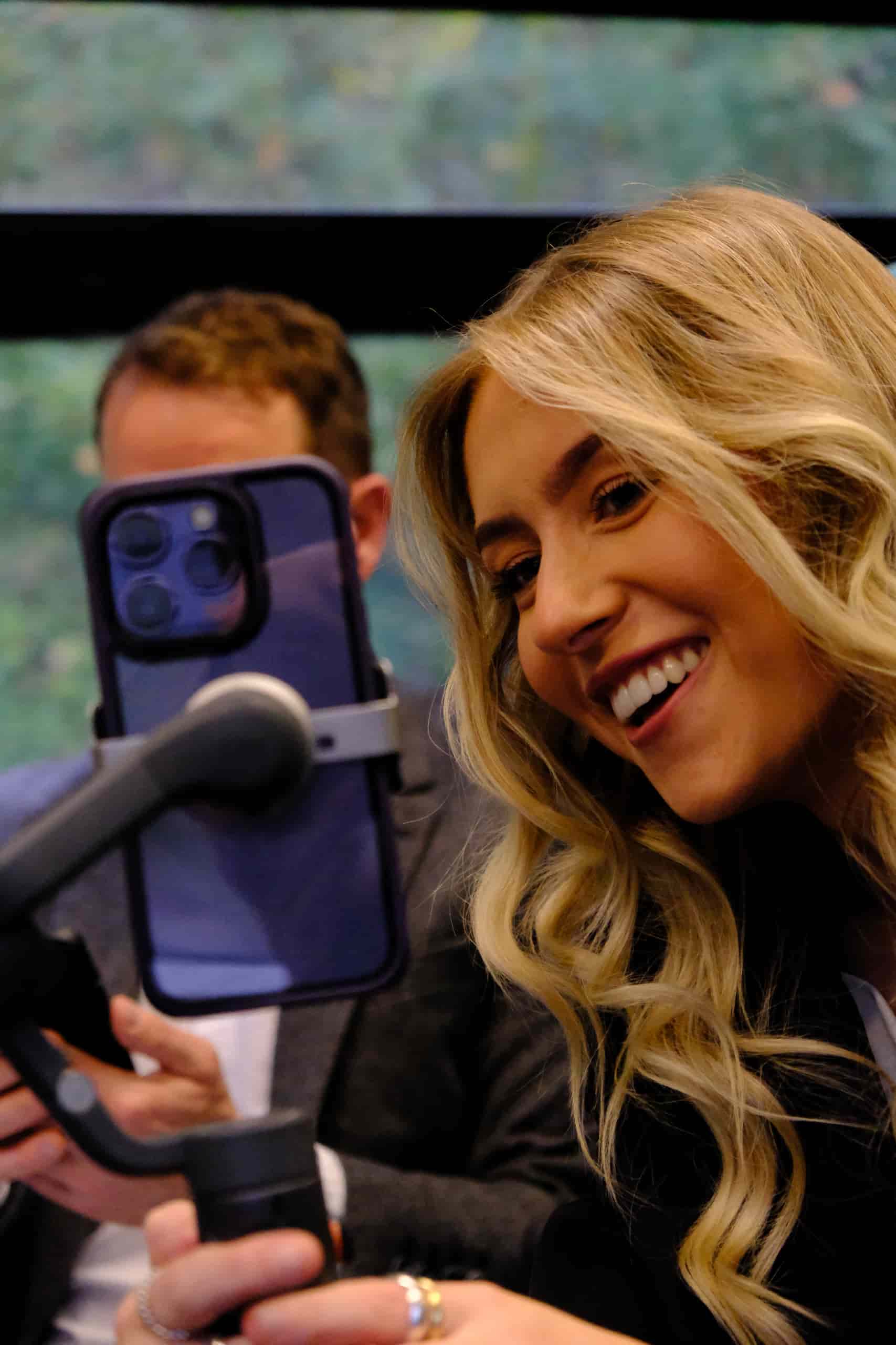 Ellie, a content creator, smiling while recording content on a smartphone mounted on a handheld stabiliser.